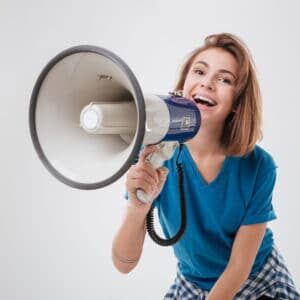 Portrait of a casual excited woman screaming in loudspeaker isolated on a white background